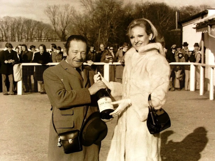 Lyn Paul presenting trainer Fred Winter with a magnum of champagne at Kempton Park Racecourse, 26th February 1977.
